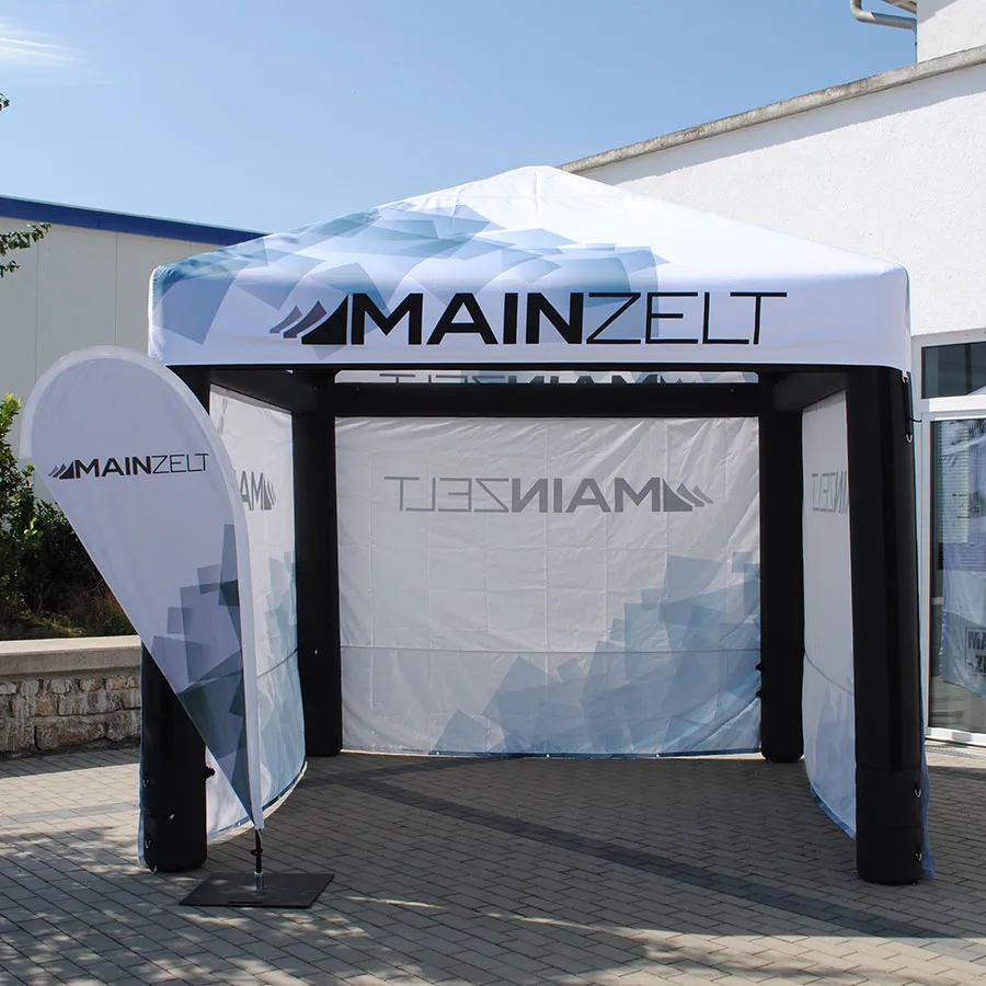 Aufblasbarer Pavillon mit bedrucktem Dach, Seitenwänden und Beachflag vor einem Firmengebäude