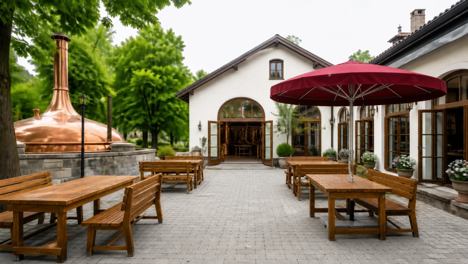 Runder roter Schirm über Holztischen in einem Brauerei-Innenhof